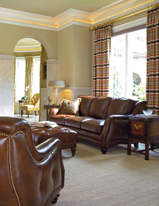a living room with a brown leather couch and chairs