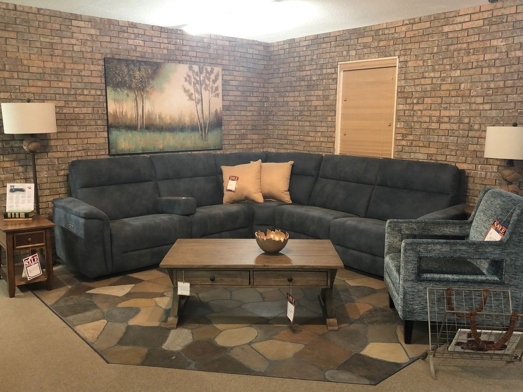 a living room with a sectional couch , chair , coffee table and rug .