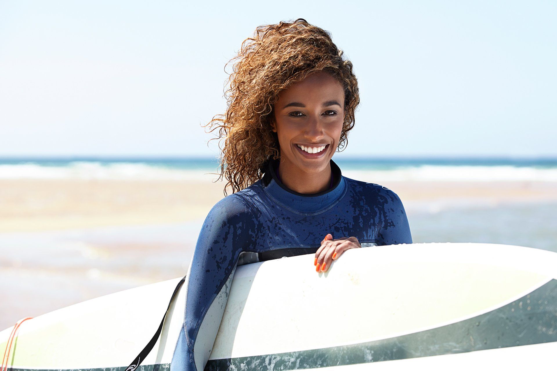woman smiling and getting ready to surf