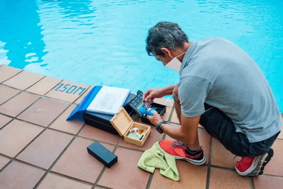 Expert technician testing backyard swimming pool water chemistry.