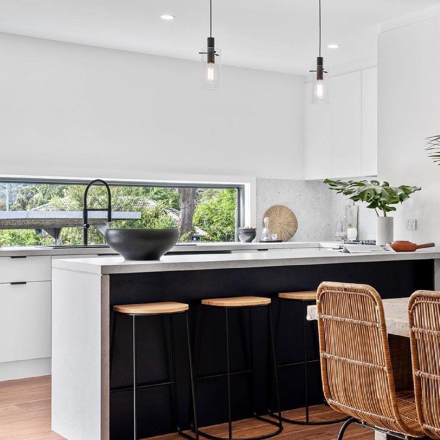 A Kitchen With a Large Island and Wicker Chairs — Paiano Custom Kitchens In Corrimal, NSW