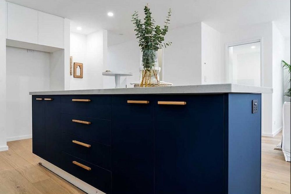 A Kitchen With Blue Cabinets and a Vase of Flowers on the Counter — Paiano Custom Kitchens In Corrimal, NSW