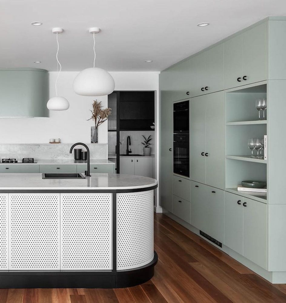 Modern custom kitchen with soft green cabinetry, integrated appliances, open shelving, and a curved 
