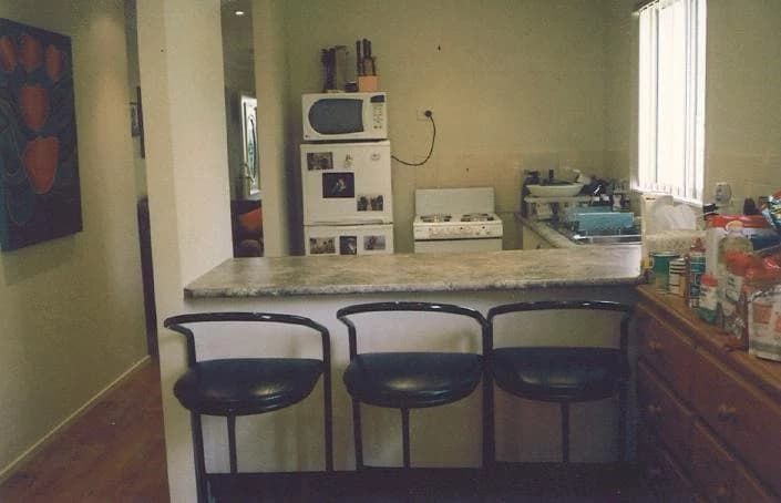 A Kitchen With Three Bar Stools and a Refrigerator — Paiano Custom Kitchens In Corrimal, NSW