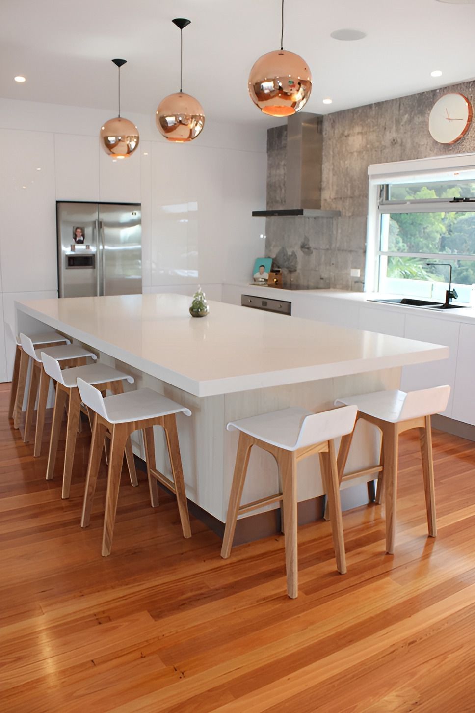 A Kitchen With a Large Island and Wooden Stools — Paiano Custom Kitchens In Corrimal, NSW