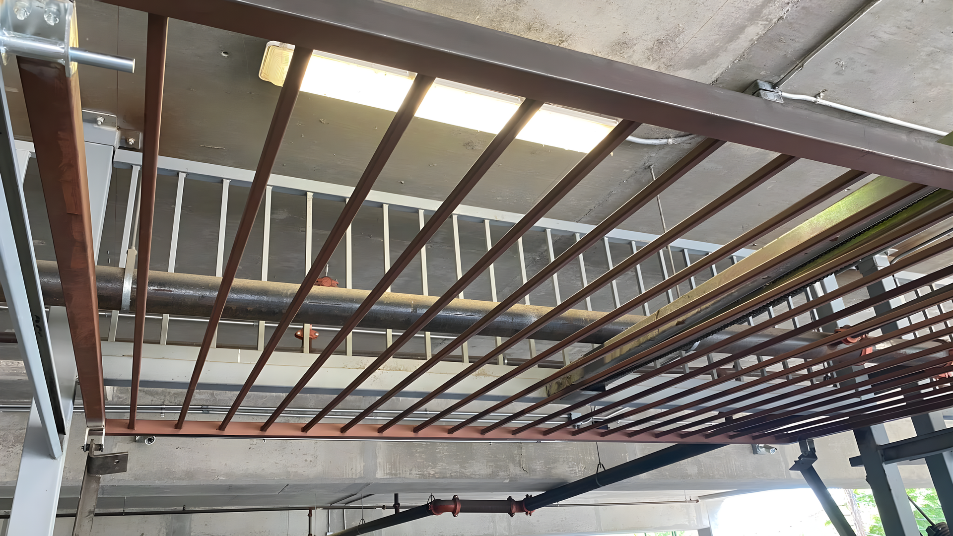 Metal ceiling framework with beams and panels in an unfinished indoor industrial space