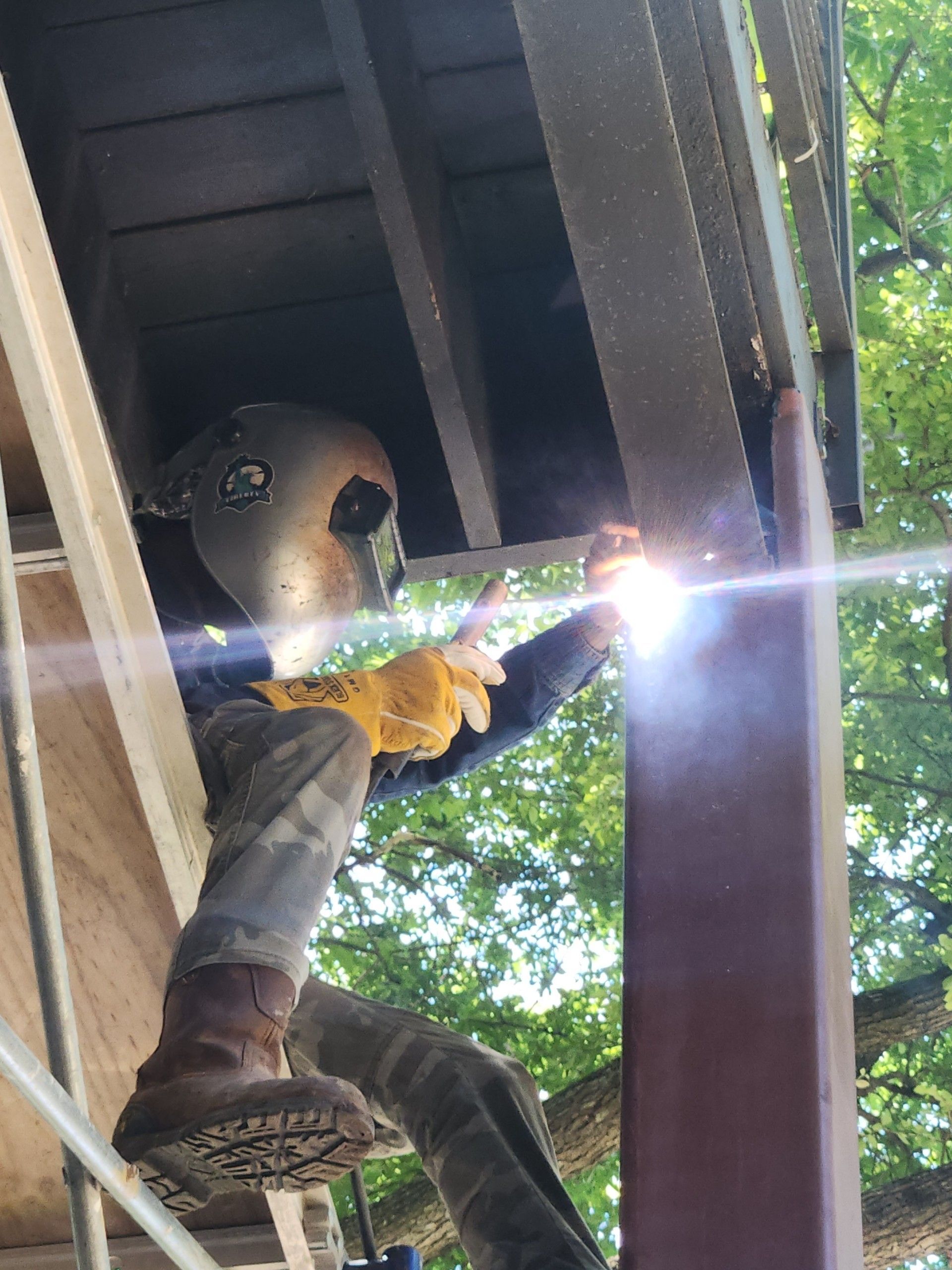 Welder in protective gear welding a large metal pipe flange in a workshop