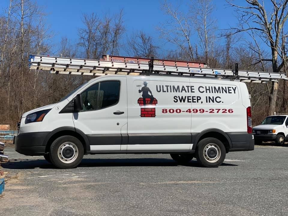 A white van with a ladder on top of it is parked in a parking lot.