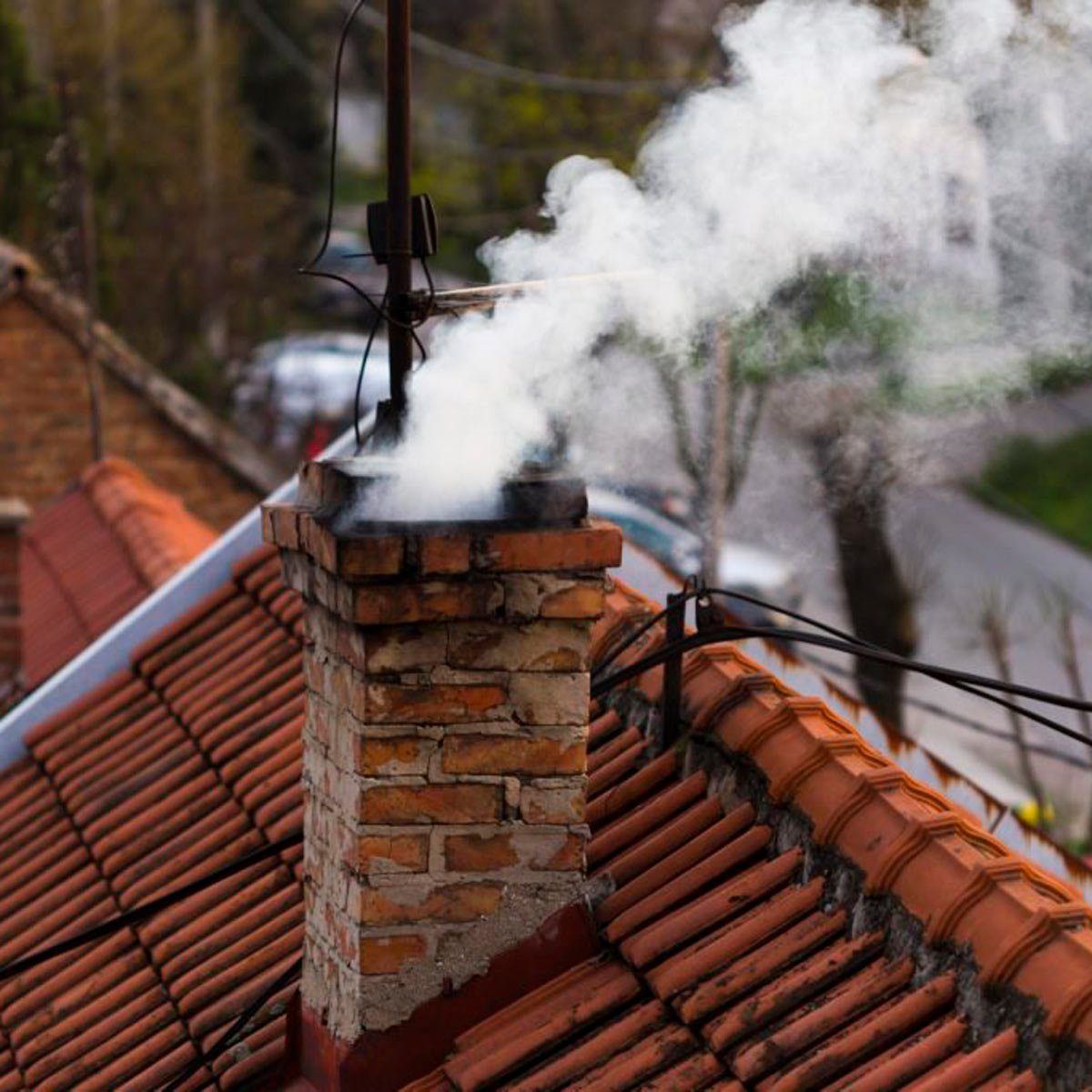 Smoke is coming out of a chimney on a tiled roof.