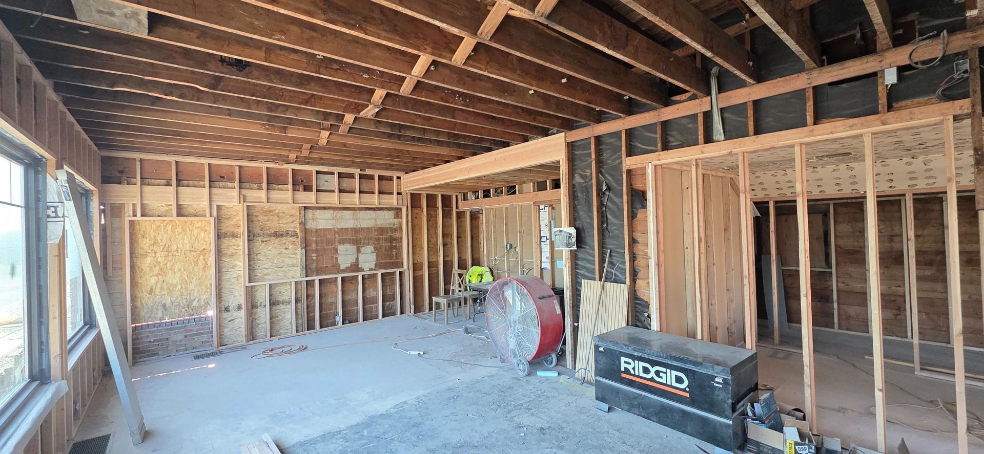 Framed room under construction with exposed wood studs, concrete floor, and a work light in the center