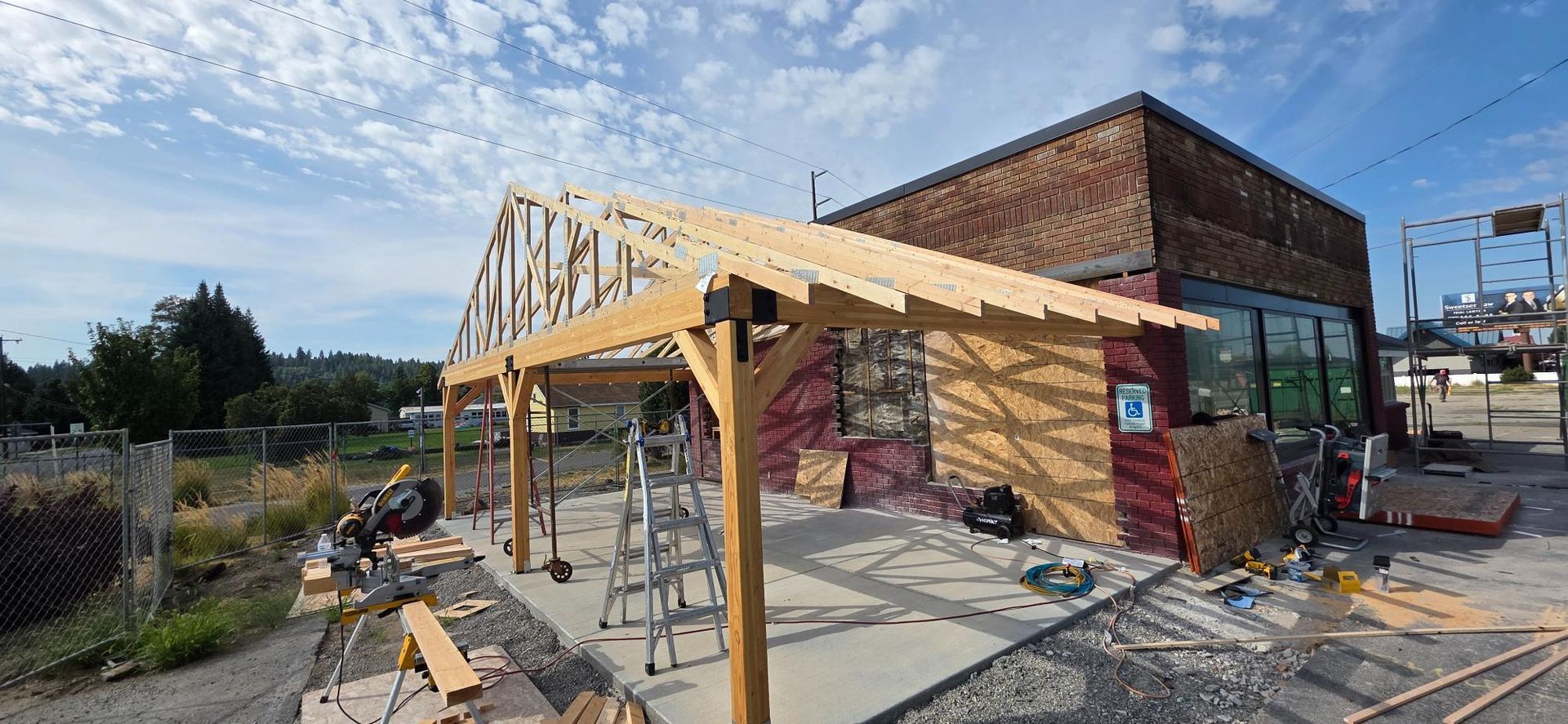Construction site with a partially built wooden structure beside a brick building