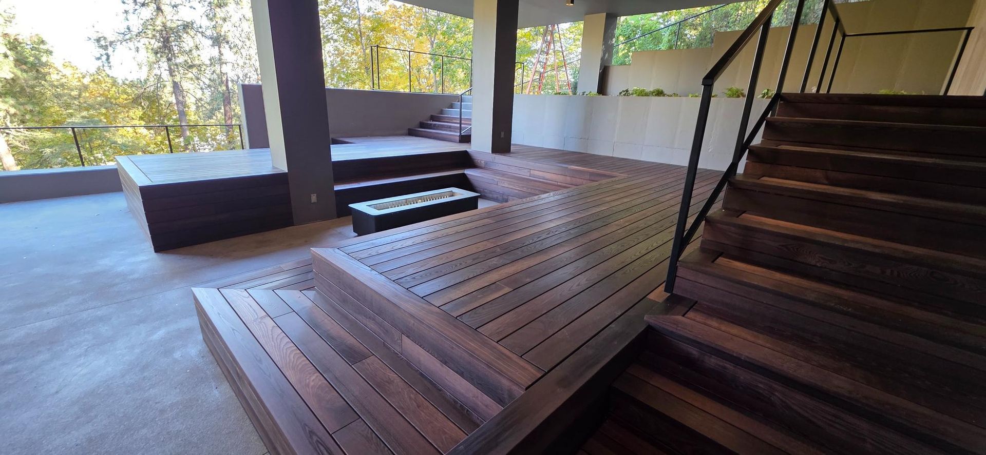 Wooden deck with steps and railings overlooking trees outside