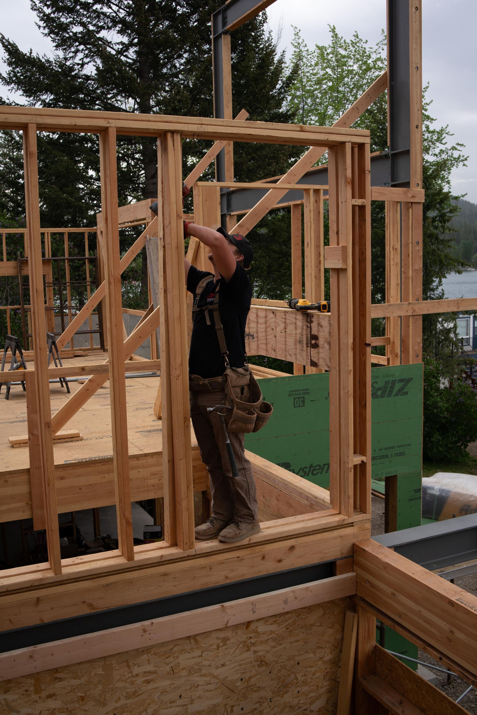 Construction worker framing a wooden house exterior on a cloudy day