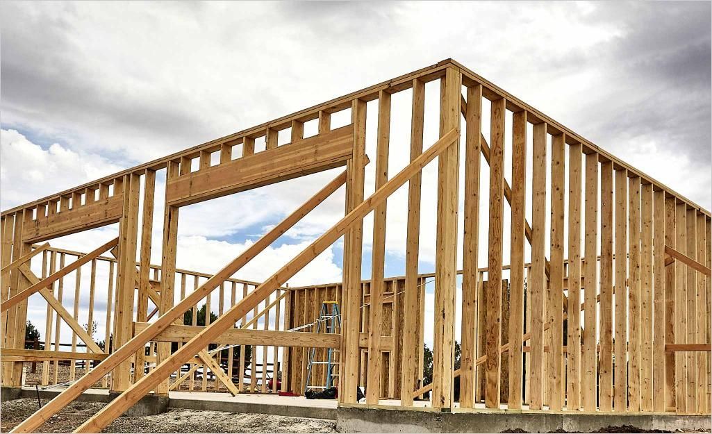 Wood-framed house under construction against a cloudy sky