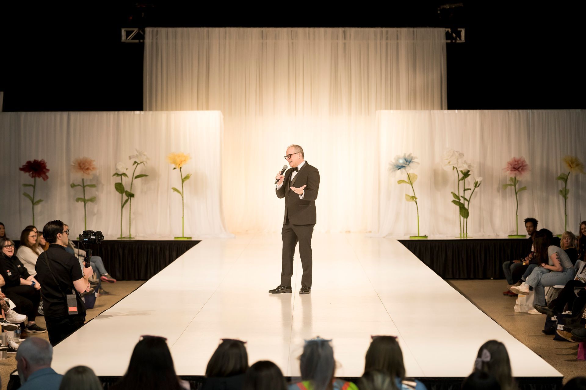 A woman in a white dress is walking down a runway.