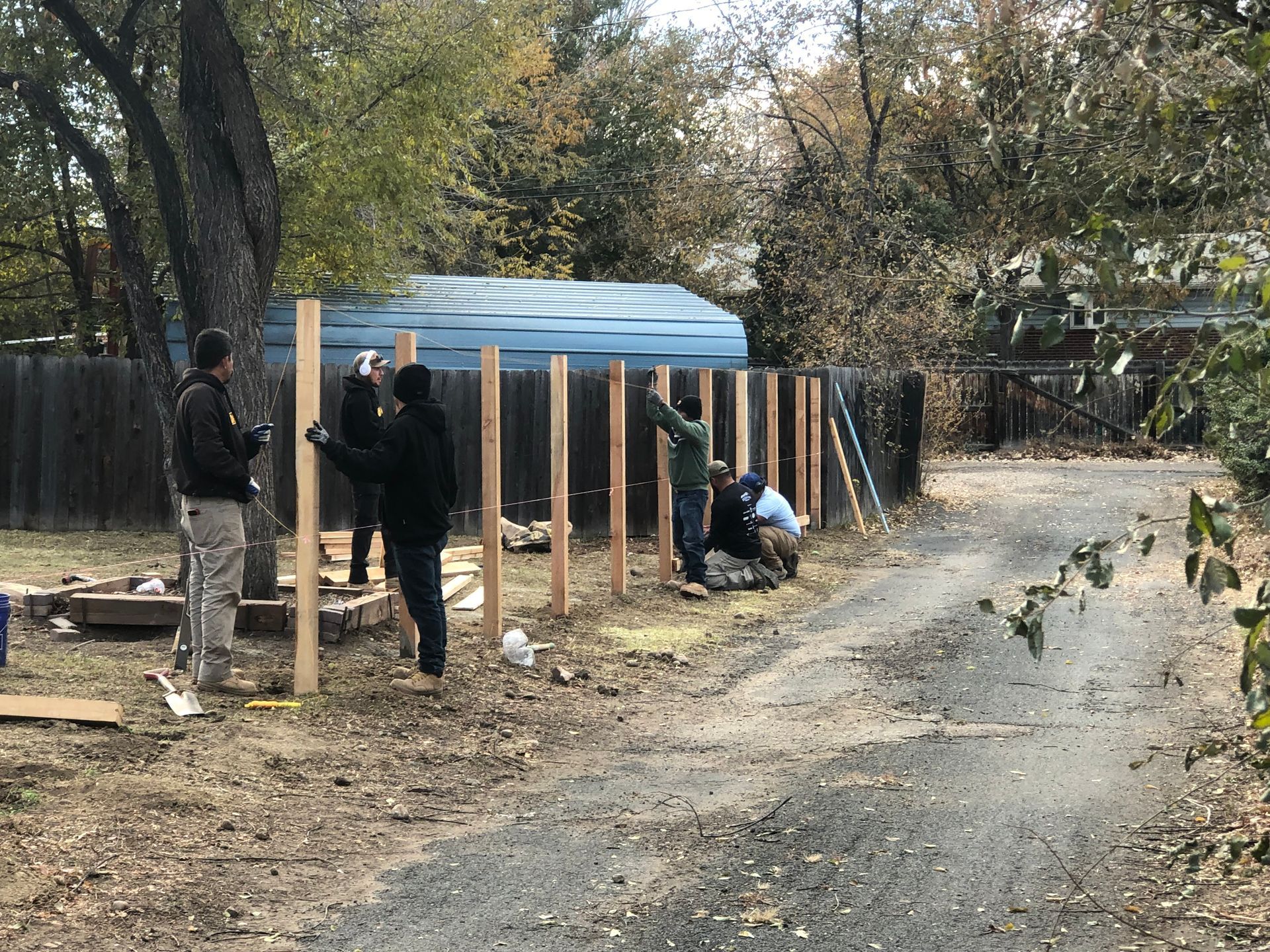 A group of people are working on a wooden fence.
