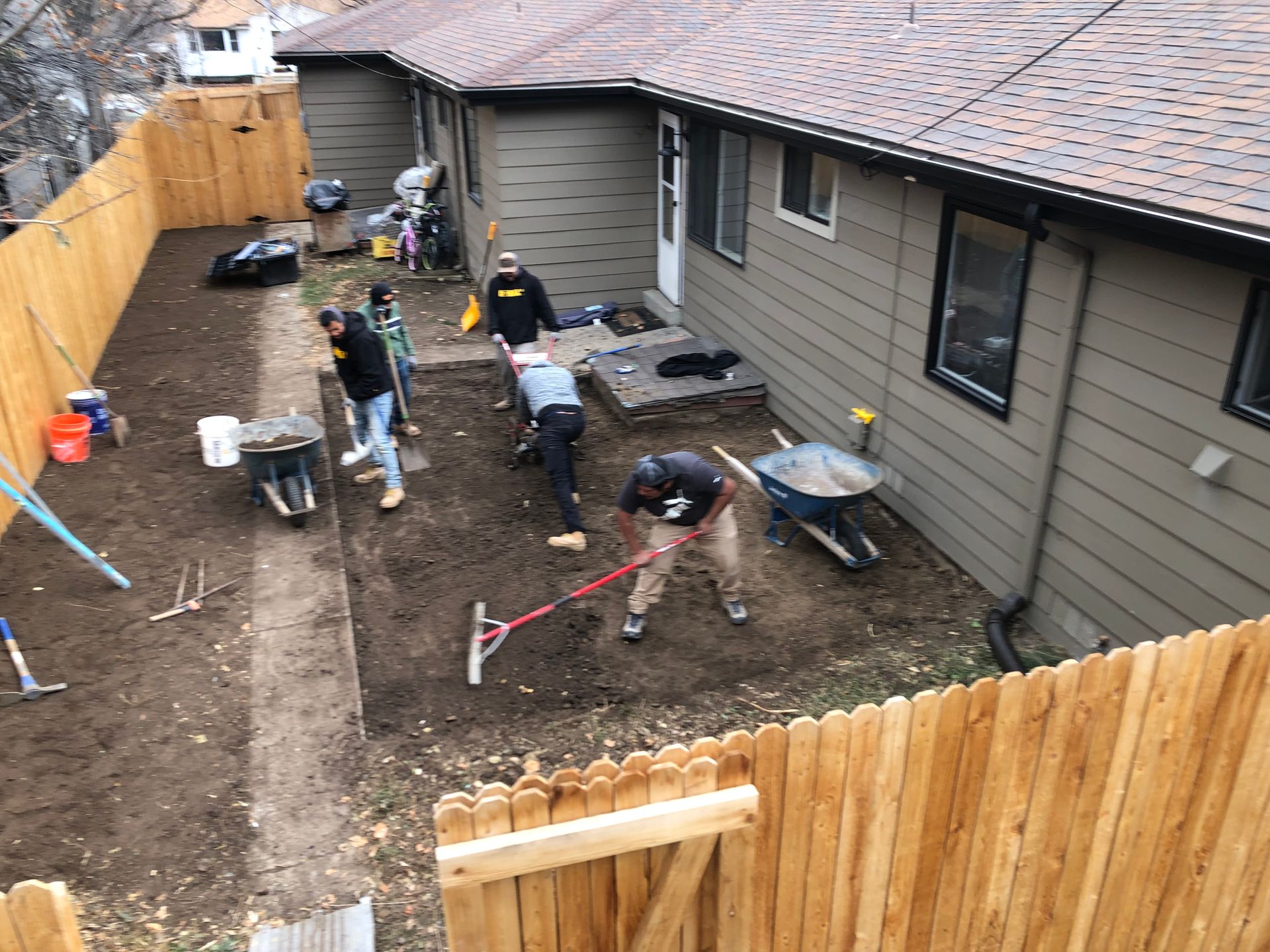 A group of people are working in the backyard of a house.