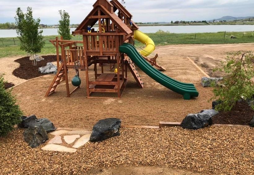 A wooden playground with a green slide and a yellow tube