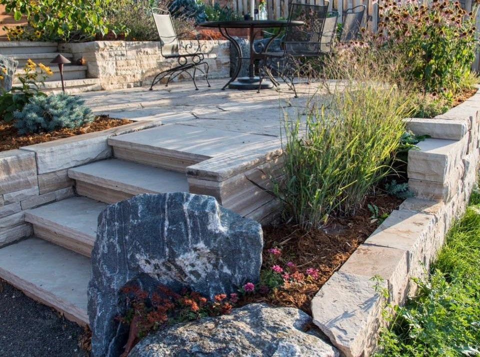 There are stairs leading up to a patio with a table and chairs.