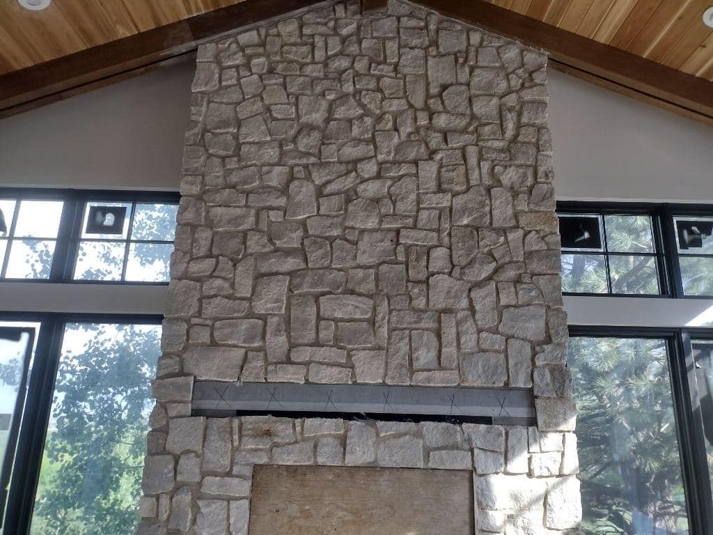 A large stone fireplace in a room with lots of windows