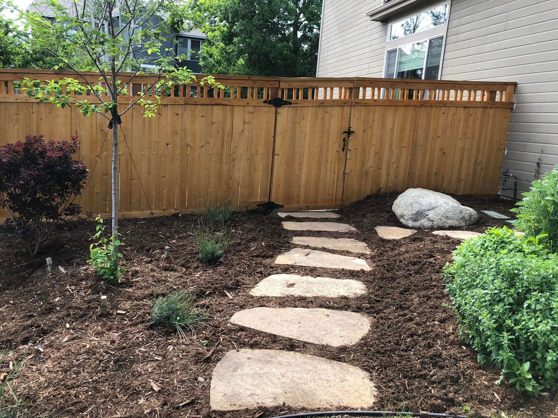 A wooden fence with a stone walkway leading to it.