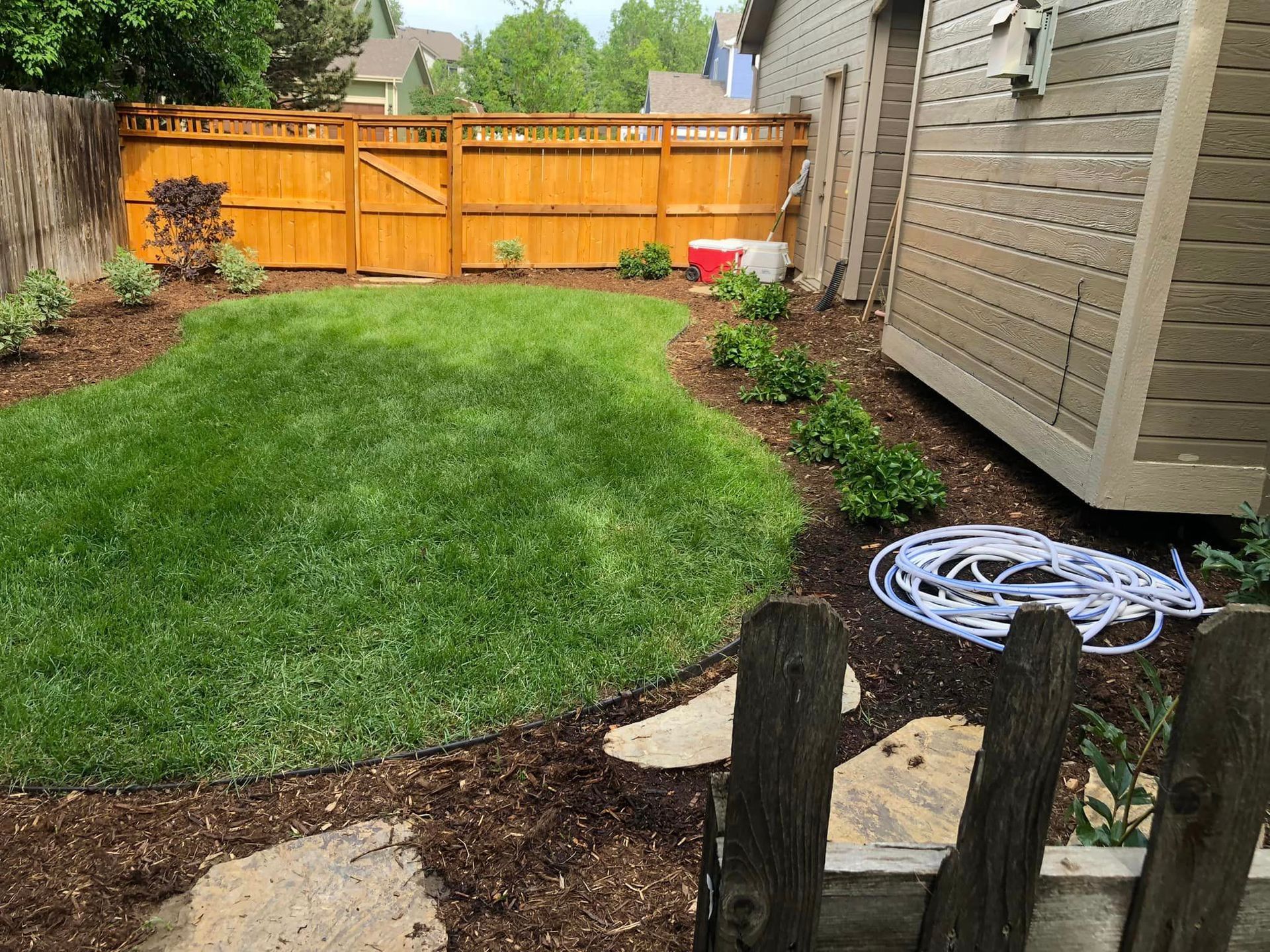 A backyard with a wooden fence and a hose.