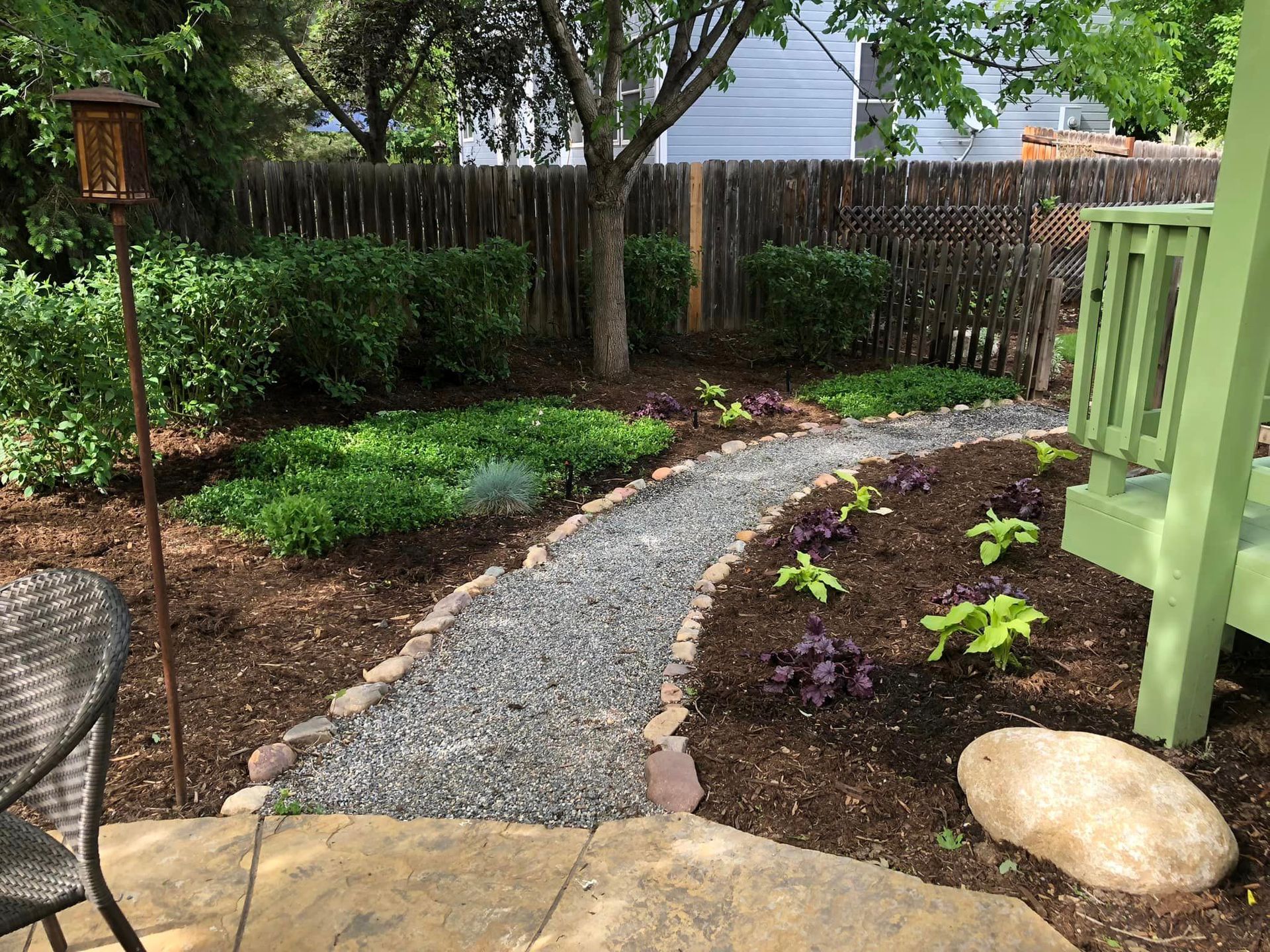 A gravel path leading to a patio with a table and chairs.