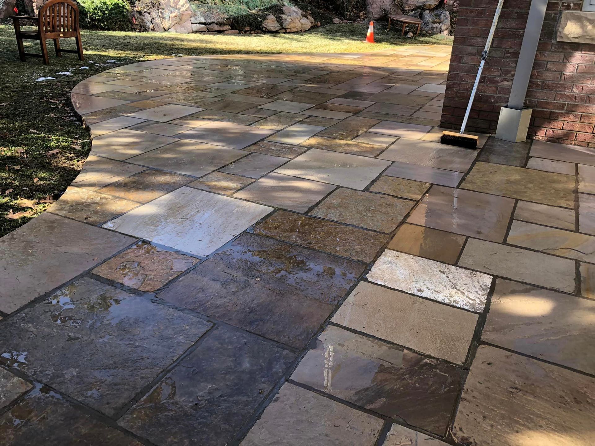 A patio with a broom and a chair in the background.