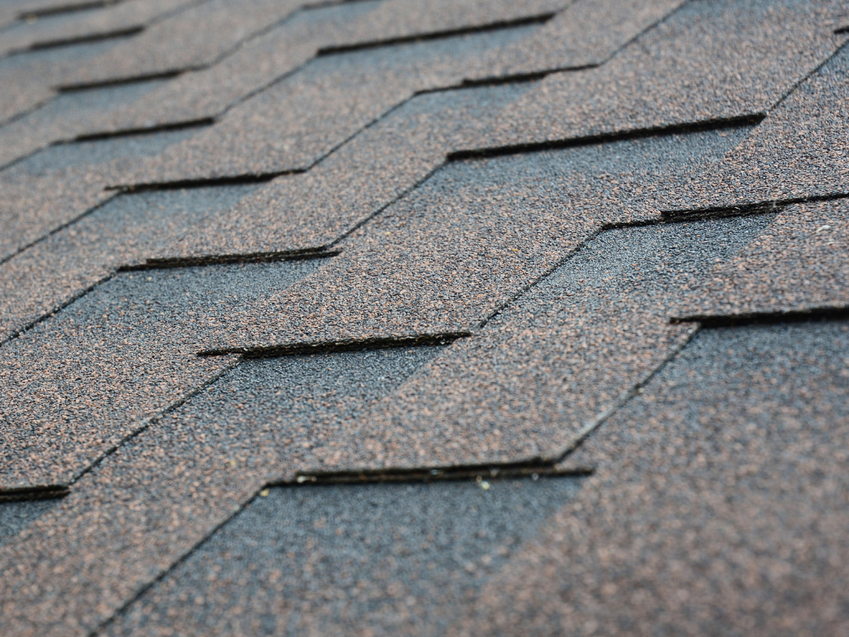 Close-up view of gray, zigzag-patterned asphalt roof shingles layered on a sloped surface.