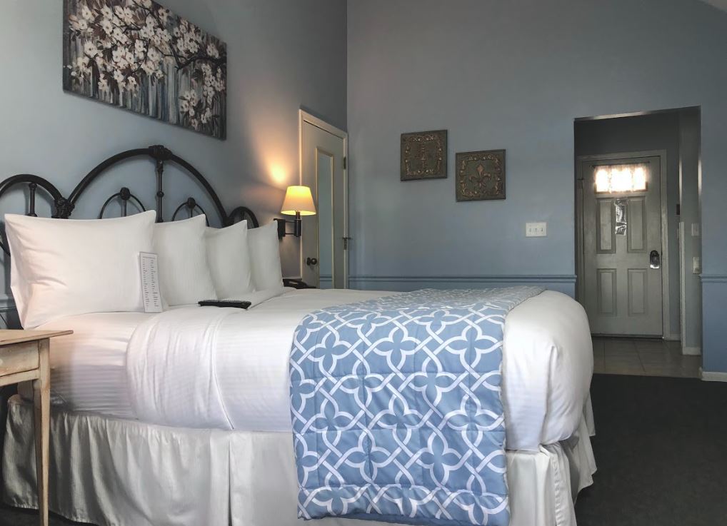 A hotel room with a king size bed and a blue blanket