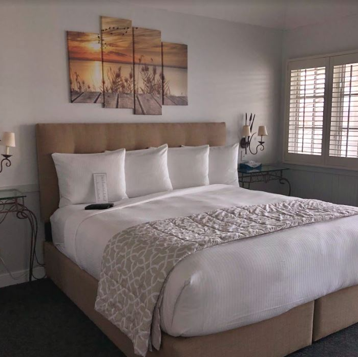 A hotel room with a large bed and a painting on the wall above it