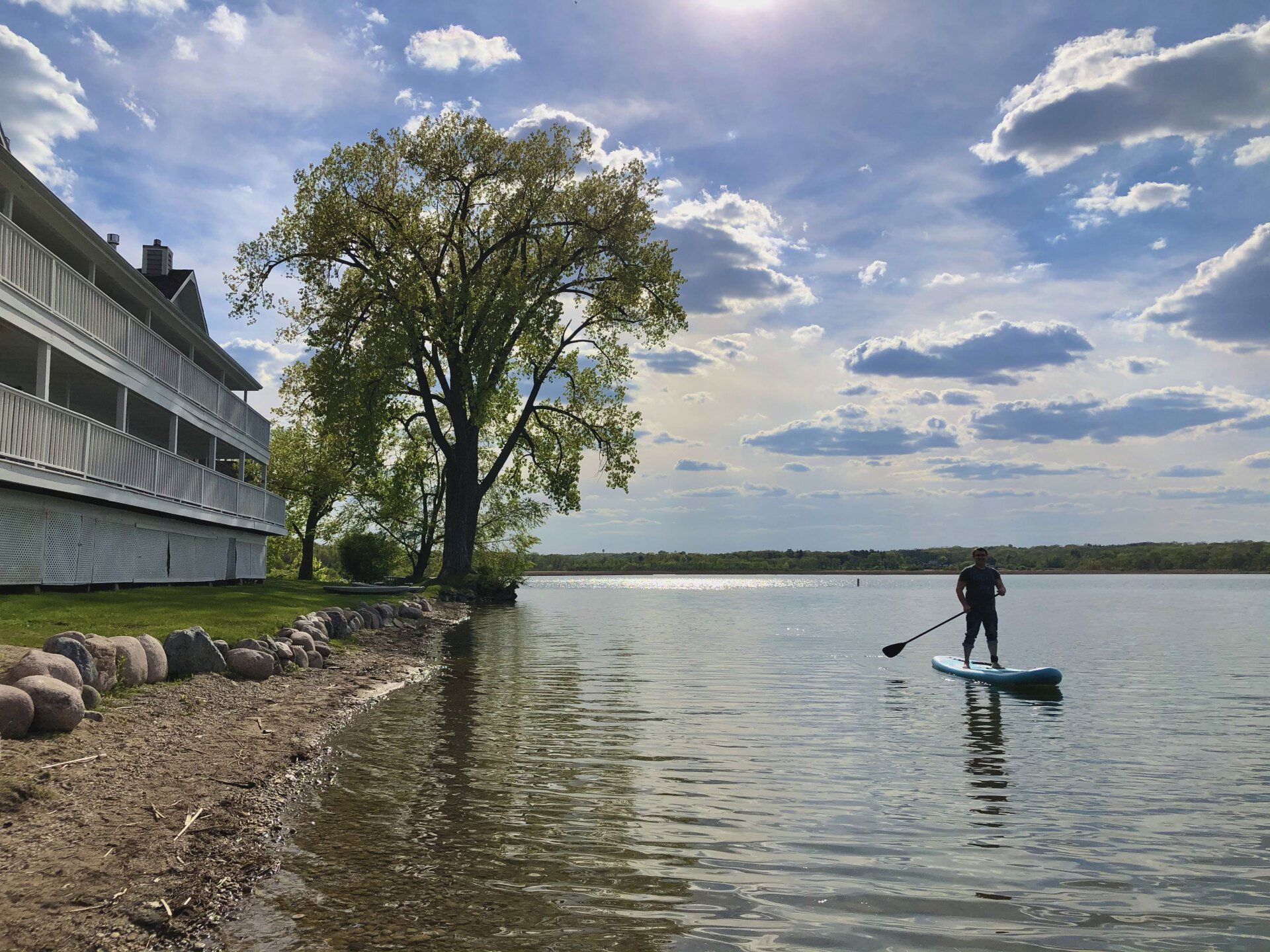 A man is standing on a paddle board in the water.