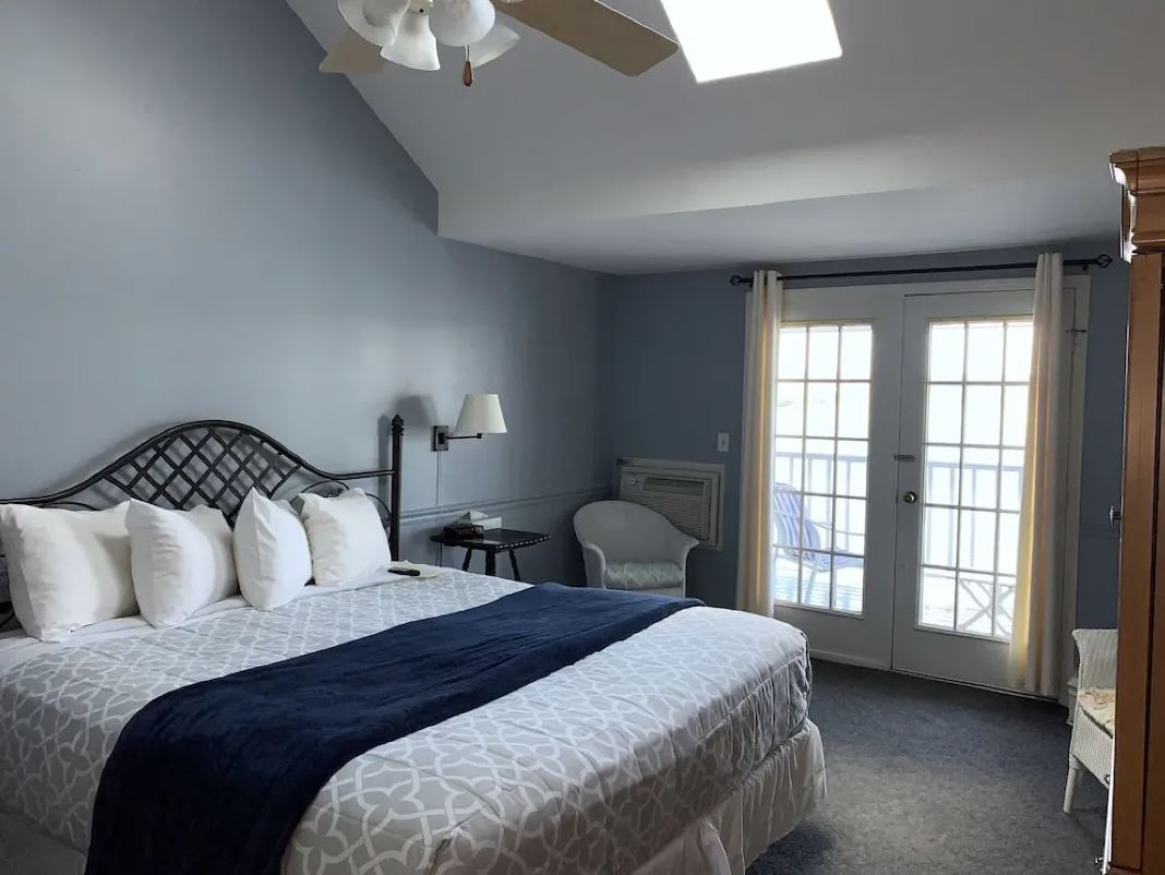 A hotel room with a king size bed and a ceiling fan.