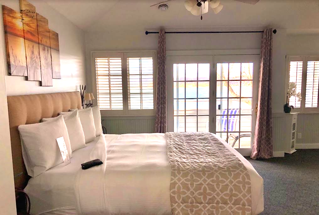 A hotel room with a king size bed and sliding glass doors.