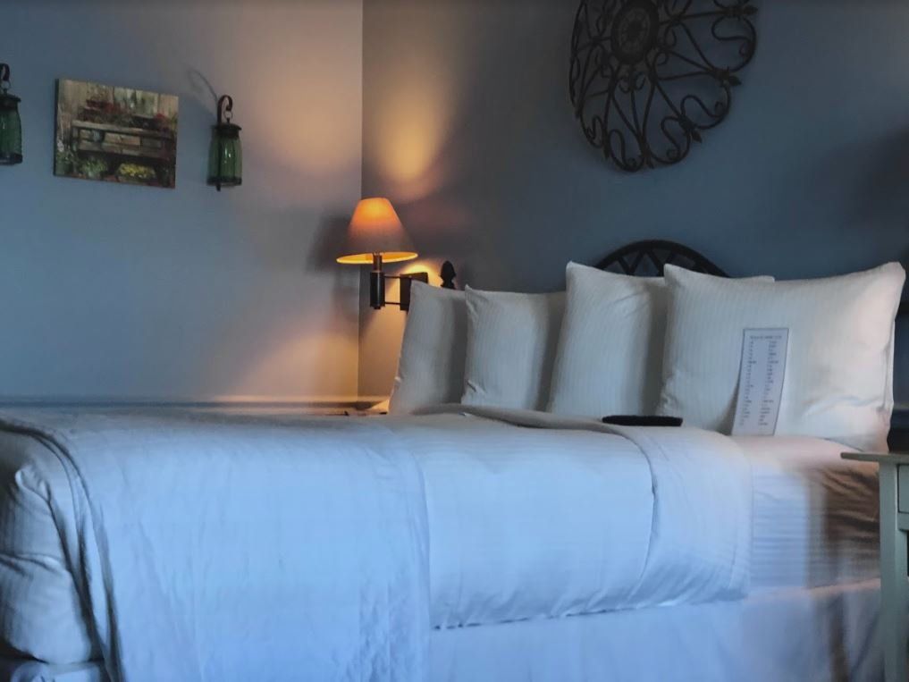 A bed with white sheets and pillows in a hotel room