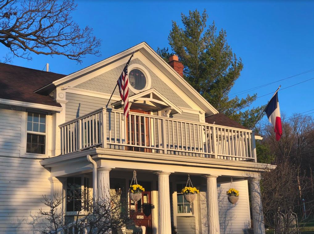 A white house with a balcony and an american flag