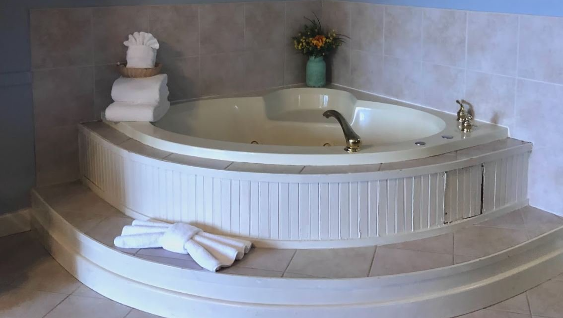 There is a large jacuzzi tub in the corner of the bathroom.