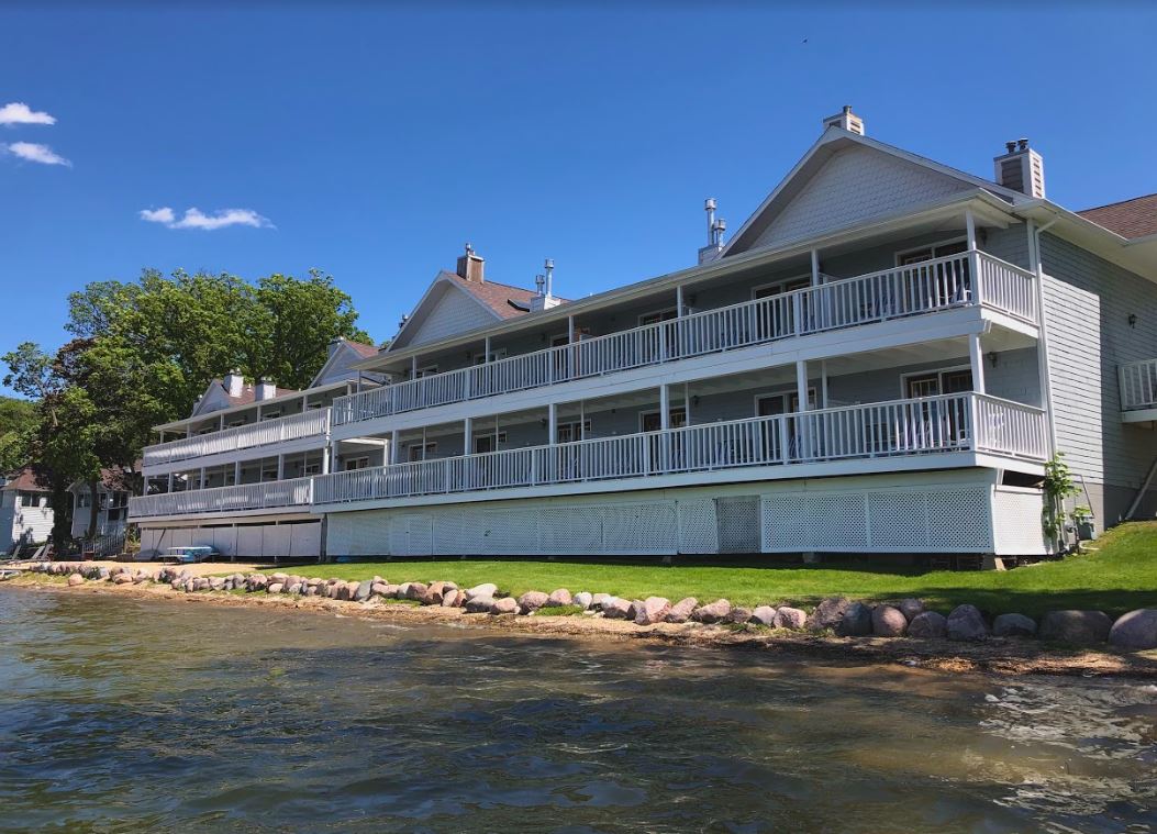 A large white house is sitting next to a body of water.