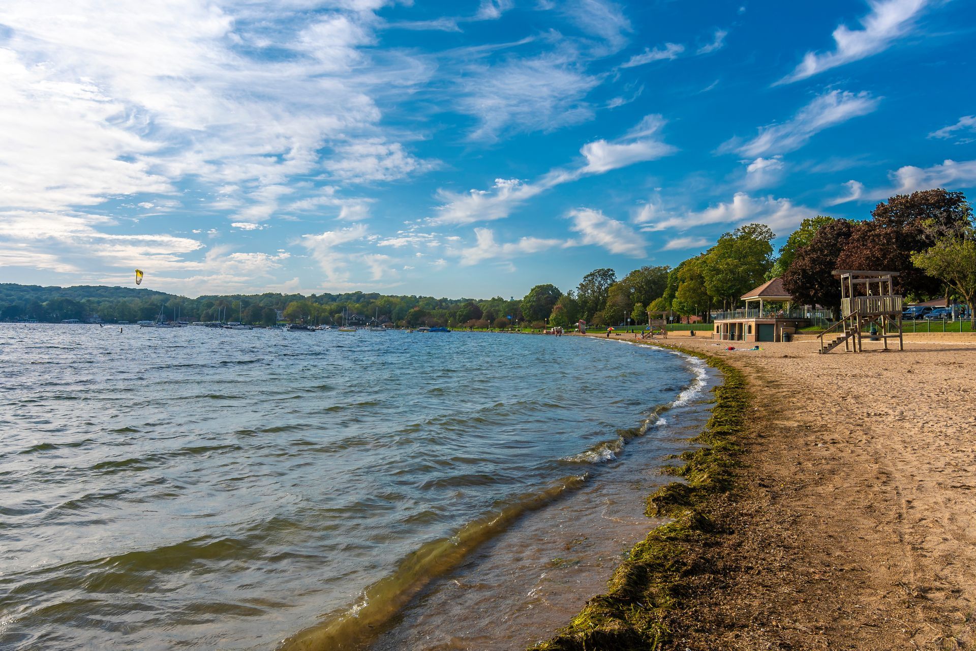 A beach with a lifeguard tower on the shore of a lake.