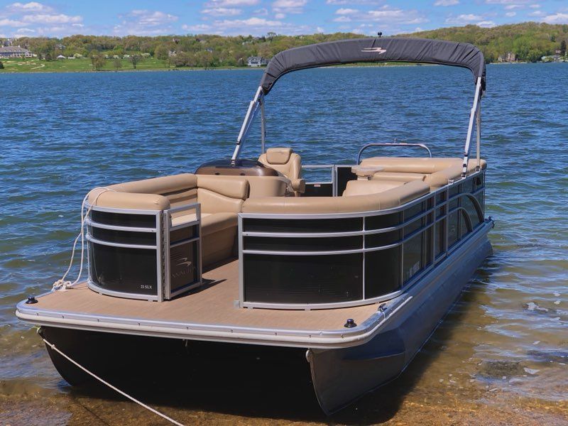 A pontoon boat is tied to the shore of a lake