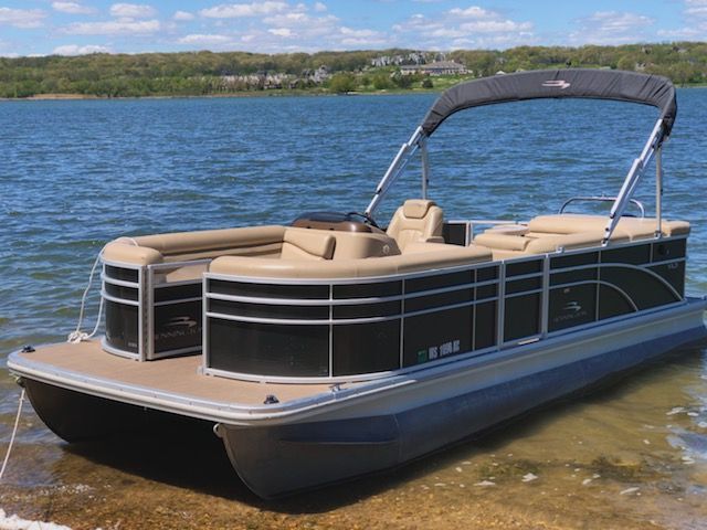 A pontoon boat is sitting on the shore of a lake