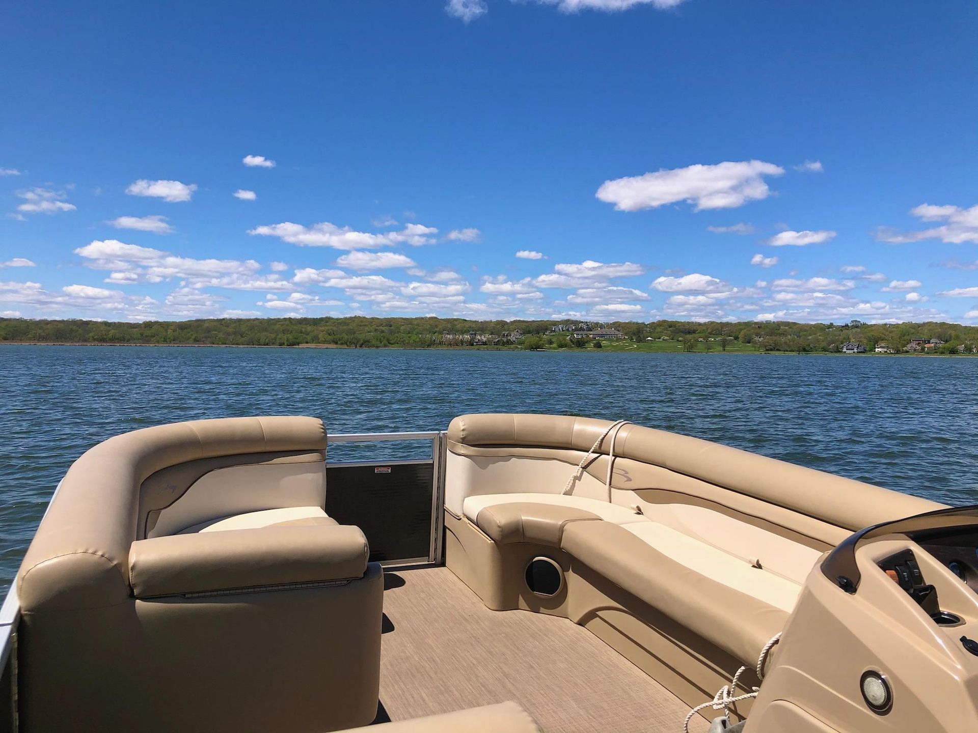 A pontoon boat is floating on a lake on a sunny day.