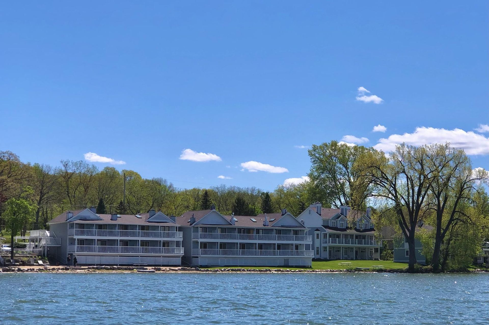 A large building sits on the shore of a lake surrounded by trees.