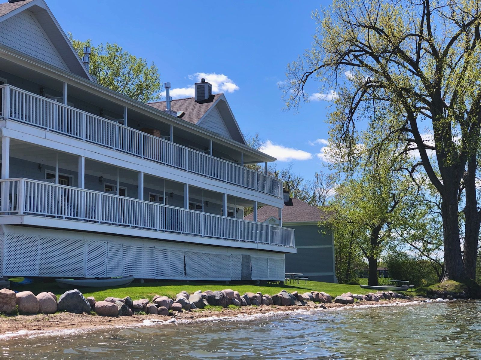 A large white house is sitting next to a body of water.