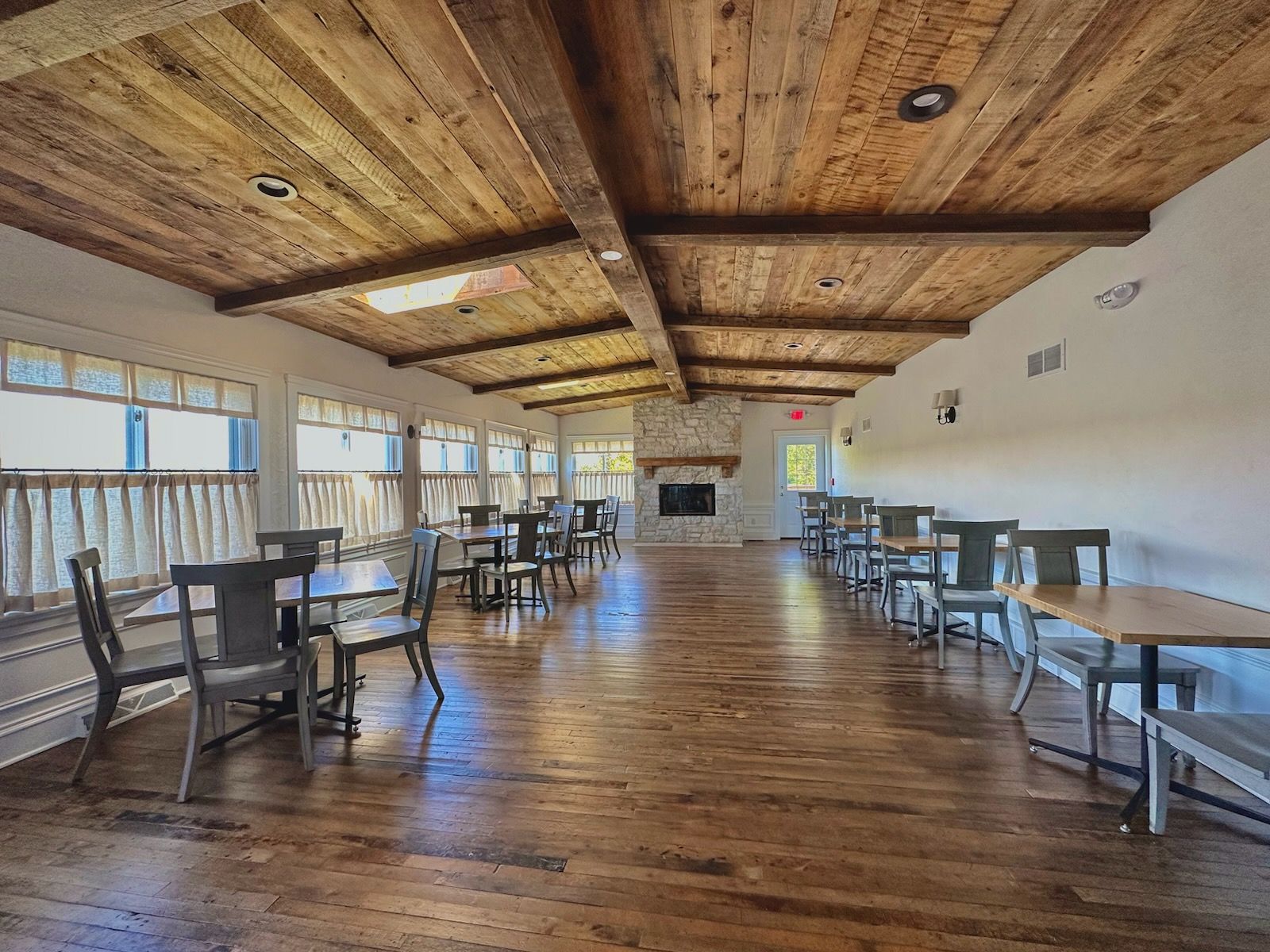 A large room with wooden floors and tables and chairs.