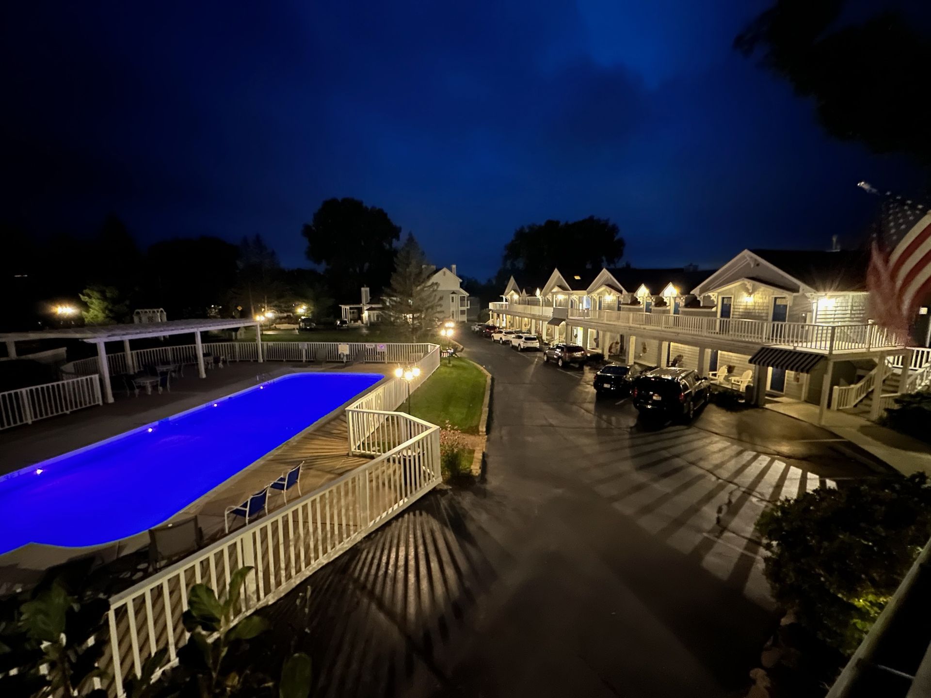 A large swimming pool is lit up at night in front of a hotel.