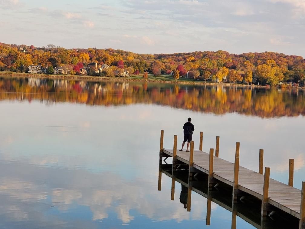 A man is standing on a dock overlooking a lake.