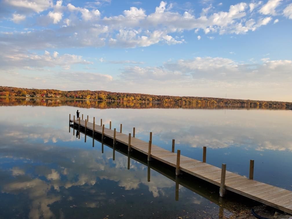 A person is standing on a dock overlooking a lake.