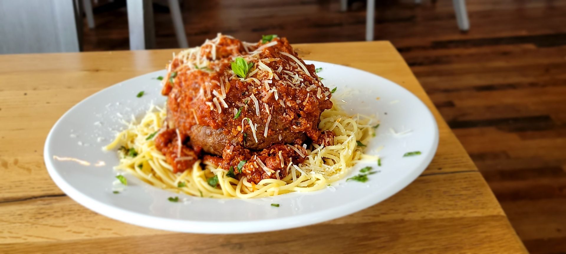 A white plate topped with spaghetti and meatballs on a wooden table.