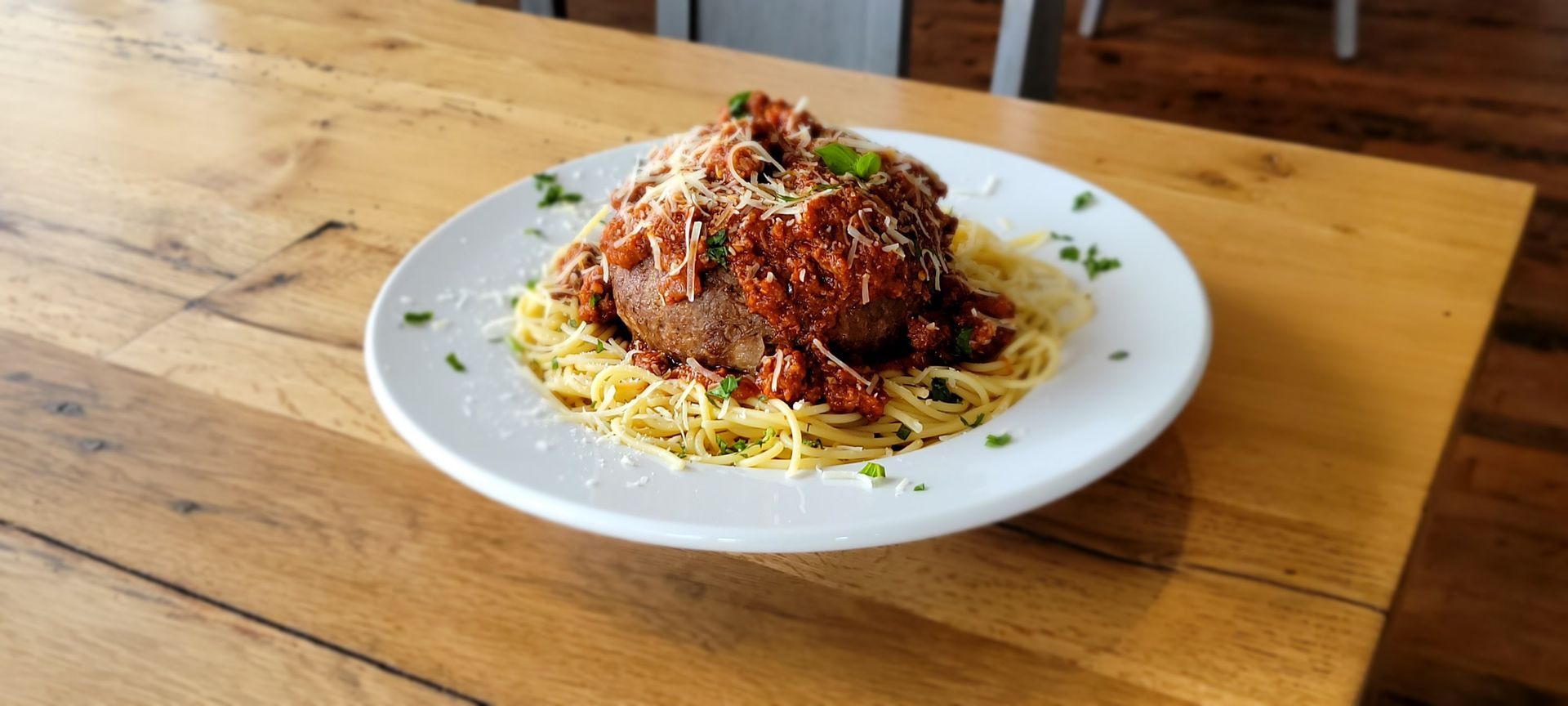 A white plate topped with spaghetti and meatballs on a wooden table.